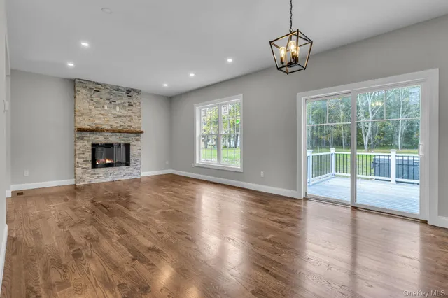 a view of an empty room with wooden floor fireplace and a window