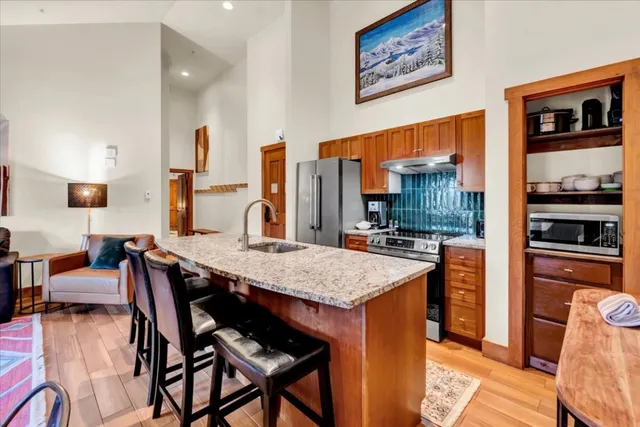 a kitchen with stainless steel appliances granite countertop a stove a refrigerator a kitchen island and chairs in it