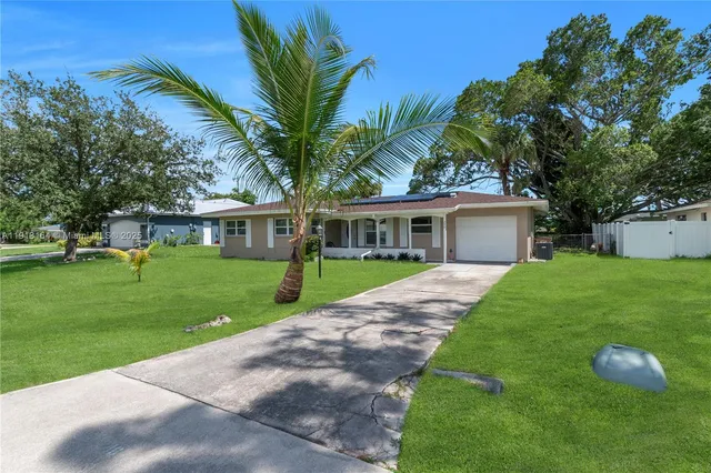 a front view of house with a garden and palm trees