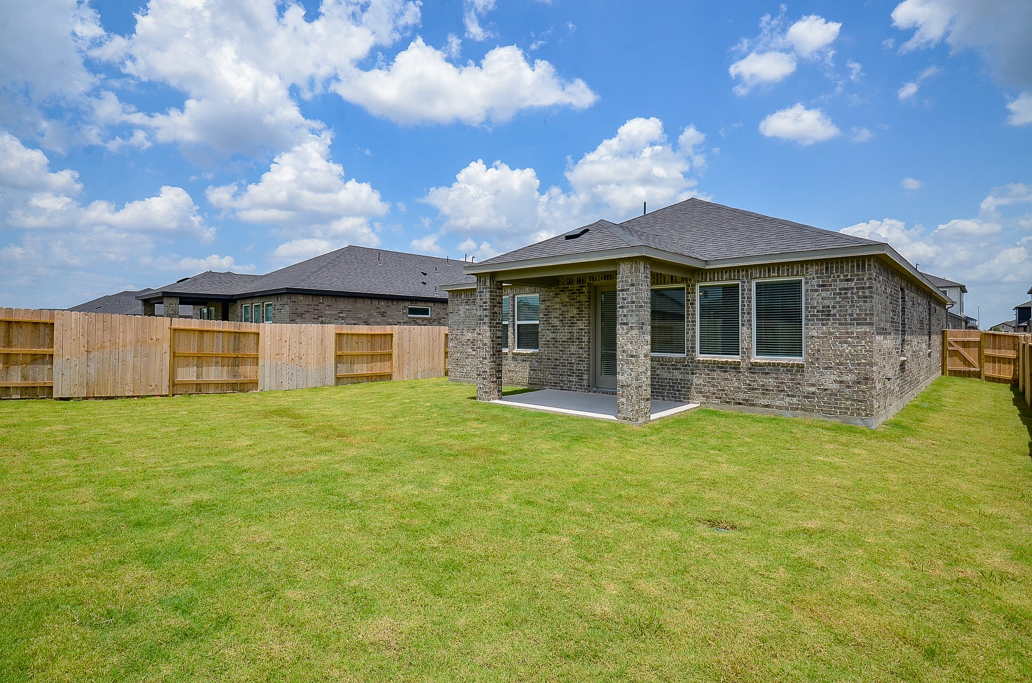 9727 Rialto Hts Drive Cypress, TX 77433 - Photo 35 of 37 Spacious backyard with a well-maintained lawn, featuring a brick house with a covered patio. Ideal for outdoor activities and relaxation.