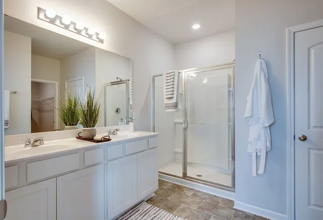 a bathroom with a double vanity sink mirror and shower