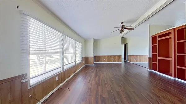 a view of empty room with wooden floor and fan