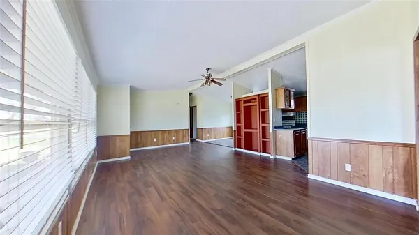 a view of empty room with wooden floor and fan