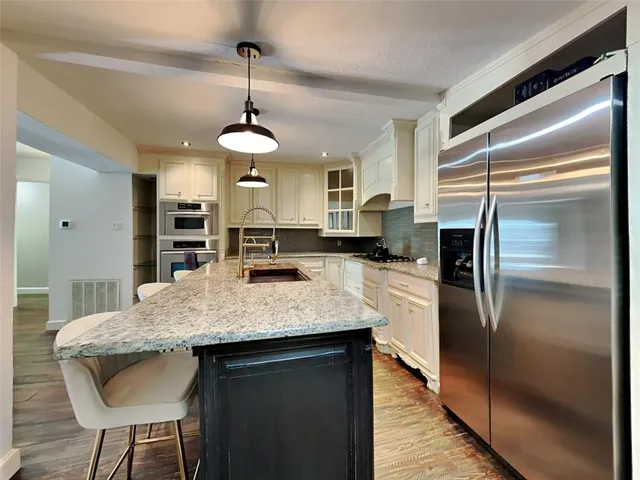 a kitchen with stainless steel appliances granite countertop a sink refrigerator and cabinets