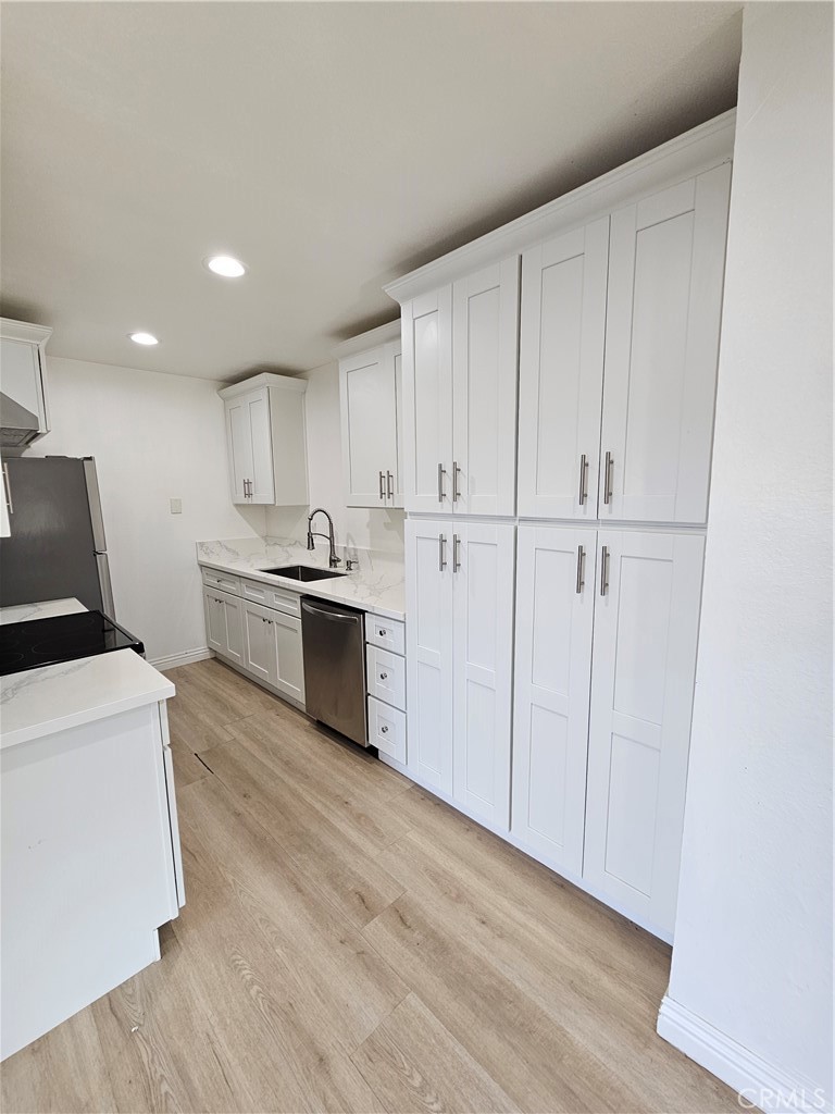 10976 Rincon Street Loma Linda, CA 92354 - Photo 5 of 12 a kitchen with white cabinets and stainless steel appliances