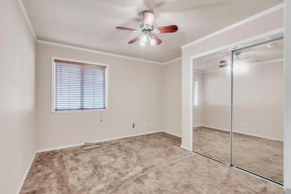 a view of an empty room and chandelier fan