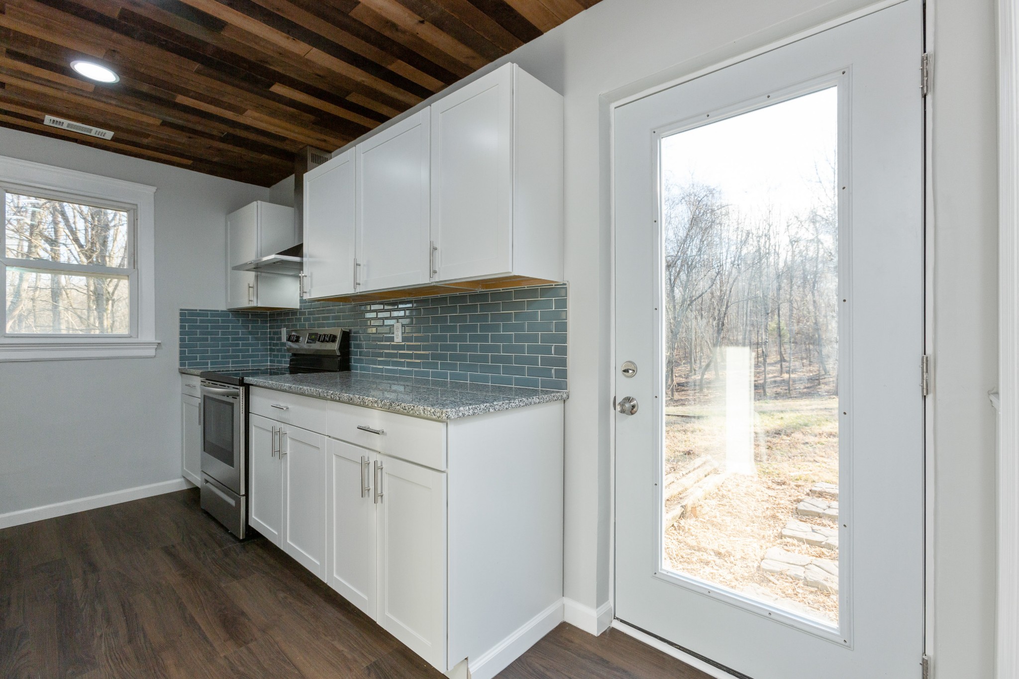6169 Highway 76 Springfield, TN 37172 - Photo 13 of 34 a kitchen with stainless steel appliances granite countertop a stove a sink and white cabinets with wooden floors