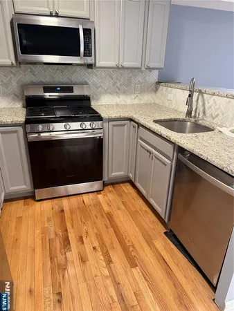 a kitchen with granite countertop a stove top oven microwave and sink
