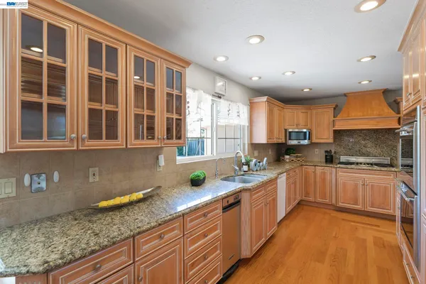 a large kitchen with a center island wooden floor stainless steel appliances and cabinets