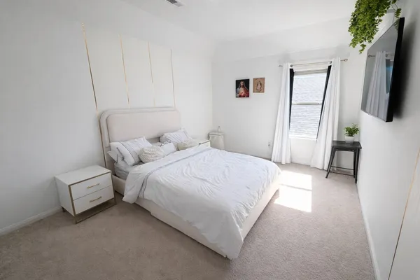 a bedroom with a bed a flat screen tv and dresser