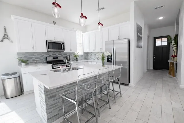 a kitchen with stainless steel appliances granite countertop a sink a stove a microwave a refrigerator and cabinets