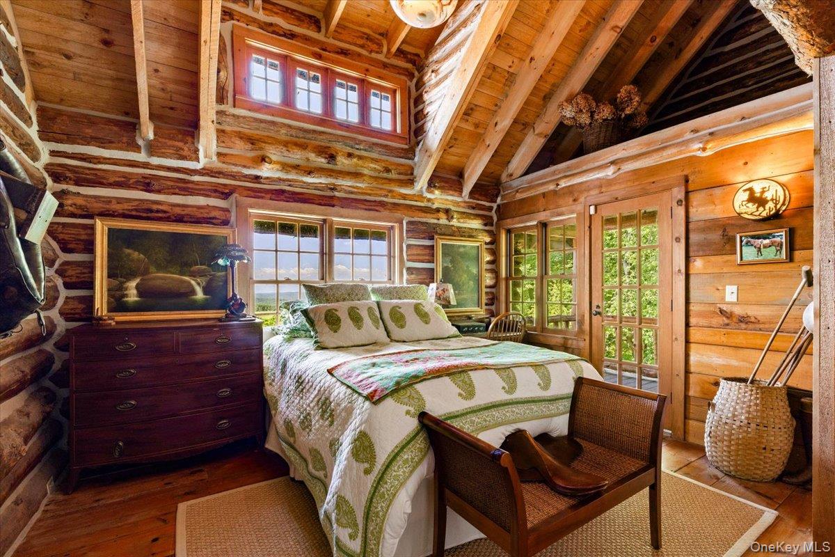 367 Prospect Hill Road Ancramdale, NY 12503 - Photo 31 of 50 Bedroom with a wooden ceiling with exposed beams, high vaulted ceiling, wood-type flooring, multiple windows, and rustic walls