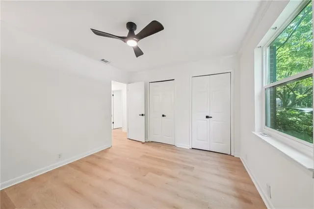 a view of a livingroom with a ceiling fan & windows