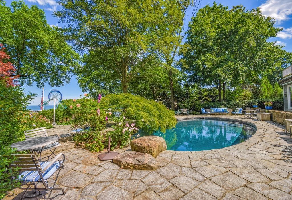 123 Long Neck Point Road Darien, CT 06820 - Photo 34 of 41 a view of a swimming pool with lawn chairs under an umbrella