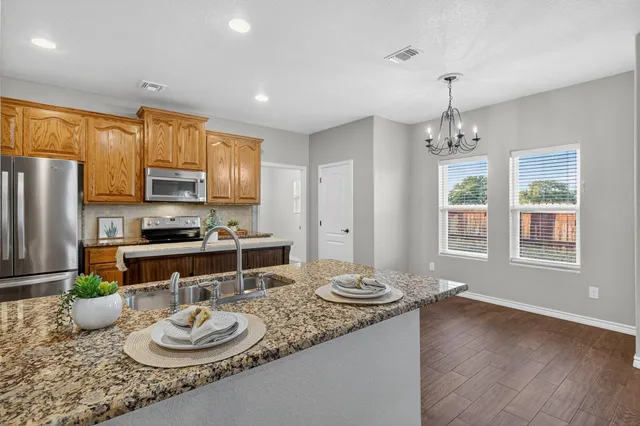 a kitchen with stainless steel appliances granite countertop a sink a stove and refrigerator