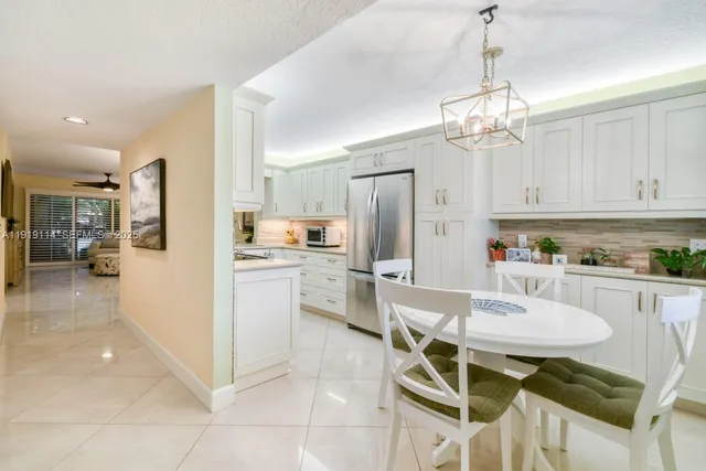 a kitchen with stainless steel appliances granite countertop a refrigerator a stove a sink dishwasher and white cabinets with wooden floor