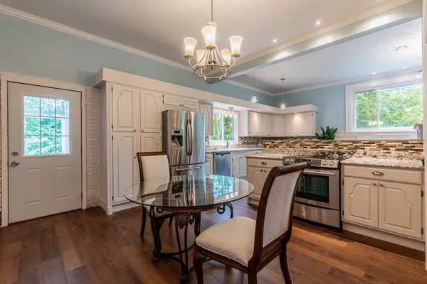 a kitchen with granite countertop a sink white cabinets and white stainless steel appliances