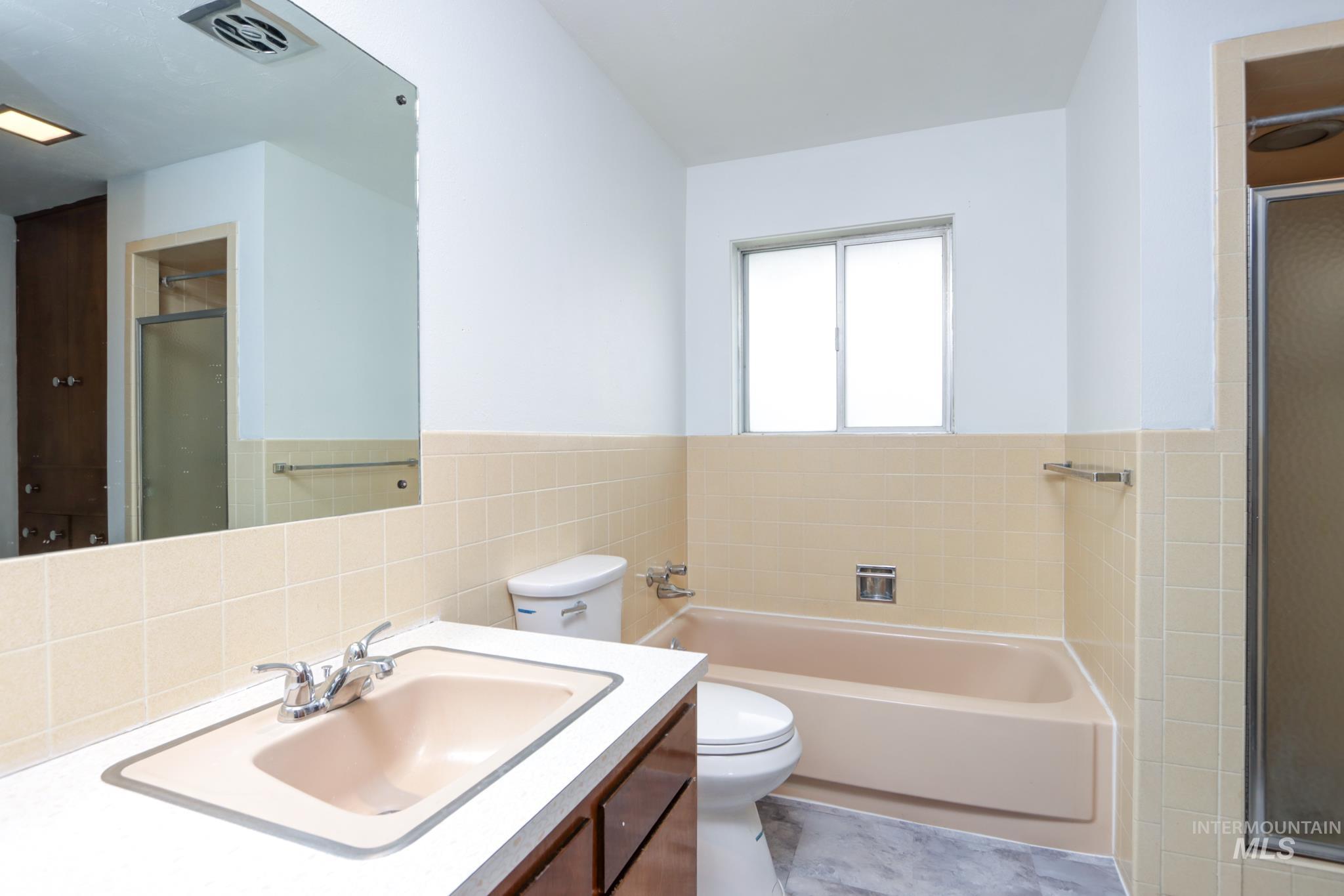 801 Thompson Avenue Nyssa, OR 97913 - Photo 19 of 46 Bathroom featuring a vanity with an integrated sink, a built-in bathtub, a toilet, and a separate shower enclosure