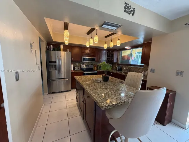 a kitchen with stainless steel appliances granite countertop a sink a refrigerator and a stove