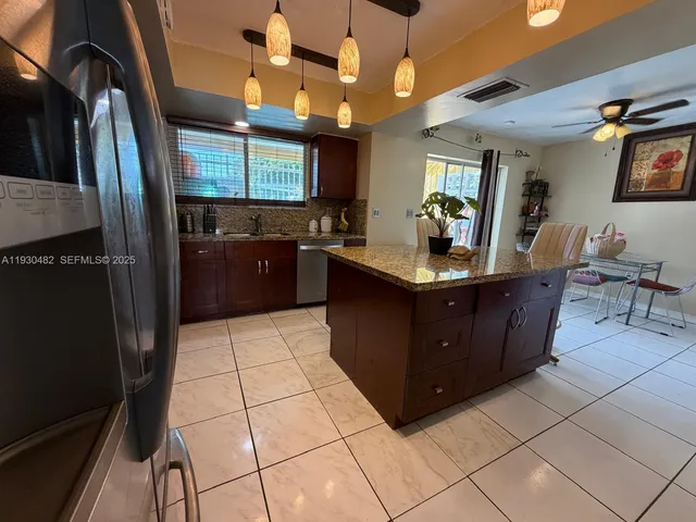 a kitchen with stainless steel appliances granite countertop a sink a microwave and a refrigerator