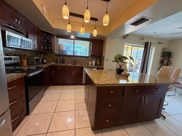 a kitchen with stainless steel appliances granite countertop a sink a refrigerator and a stove