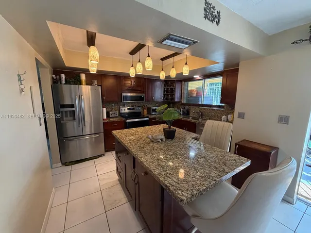 a kitchen with stainless steel appliances granite countertop a sink a stove white cabinets a dining table and chairs