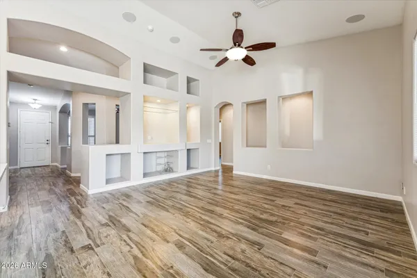 a view of an empty room with wooden floor and a ceiling fan