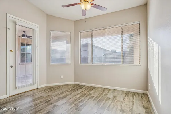 a view of an empty room with window and chandelier fan