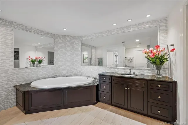 a spacious bathroom with a granite countertop double vanity sink mirror bathtub and