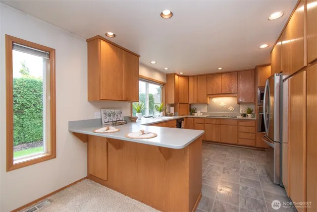 a kitchen with stainless steel appliances granite countertop a sink a stove a refrigerator cabinets and a window