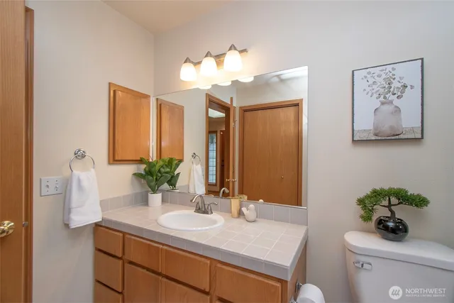 a bathroom with a granite countertop sink a toilet and a mirror