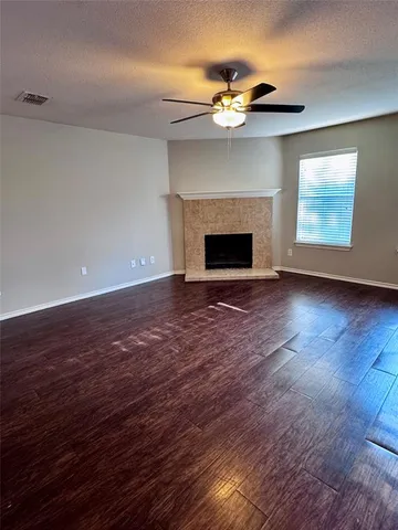 a view of an empty room with wooden floor fireplace and a window