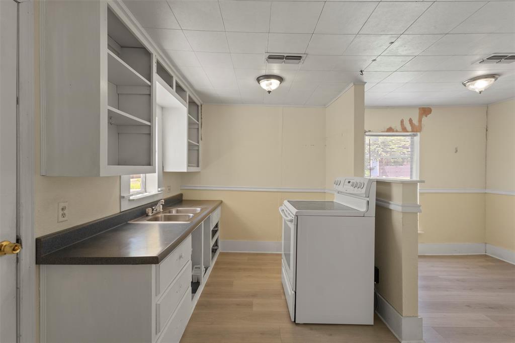 829 West 9th Street Bonham, TX 75418 - Photo 16 of 30 Kitchen area featuring light wood-finish flooring, white cabinetry, a double basin stainless steel sink, and a white electric range