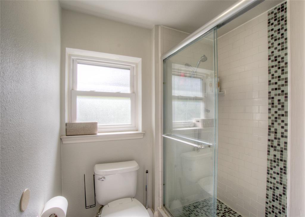 12231 Veronica Road Farmers Branch, TX 75234 - Photo 20 of 26 Shower enclosure with sliding glass door, white subway tile surround, and mosaic tile accent