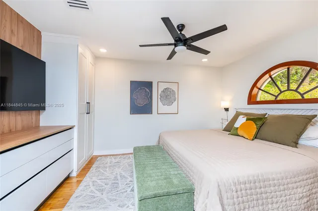 a bedroom with a bed a dresser and a flat screen tv