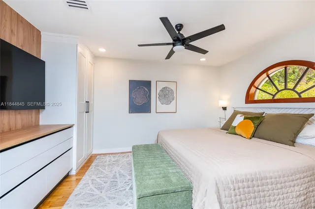 a bedroom with a bed a dresser and a flat screen tv