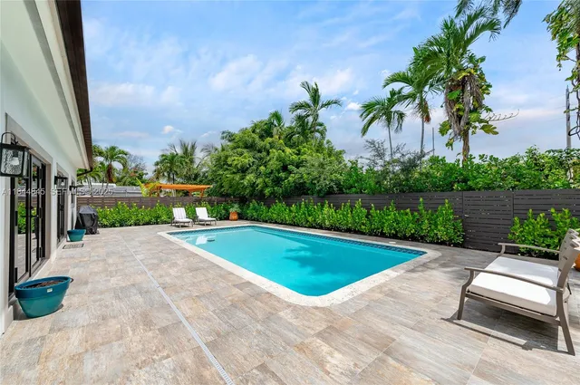 a view of a house with pool fire pit a chairs in a patio
