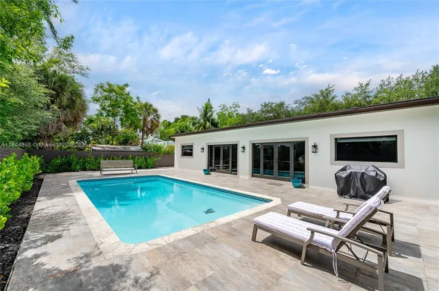 a view of a house with pool fire pit a chairs in a patio