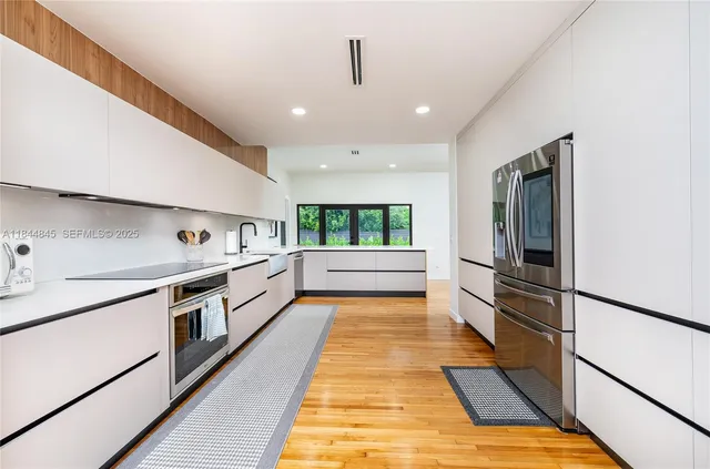 a large white kitchen with stainless steel appliances granite countertop a stove and a refrigerator