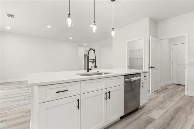 a kitchen with stainless steel appliances kitchen island granite countertop a refrigerator a stove a oven with white cabinets and wooden floor