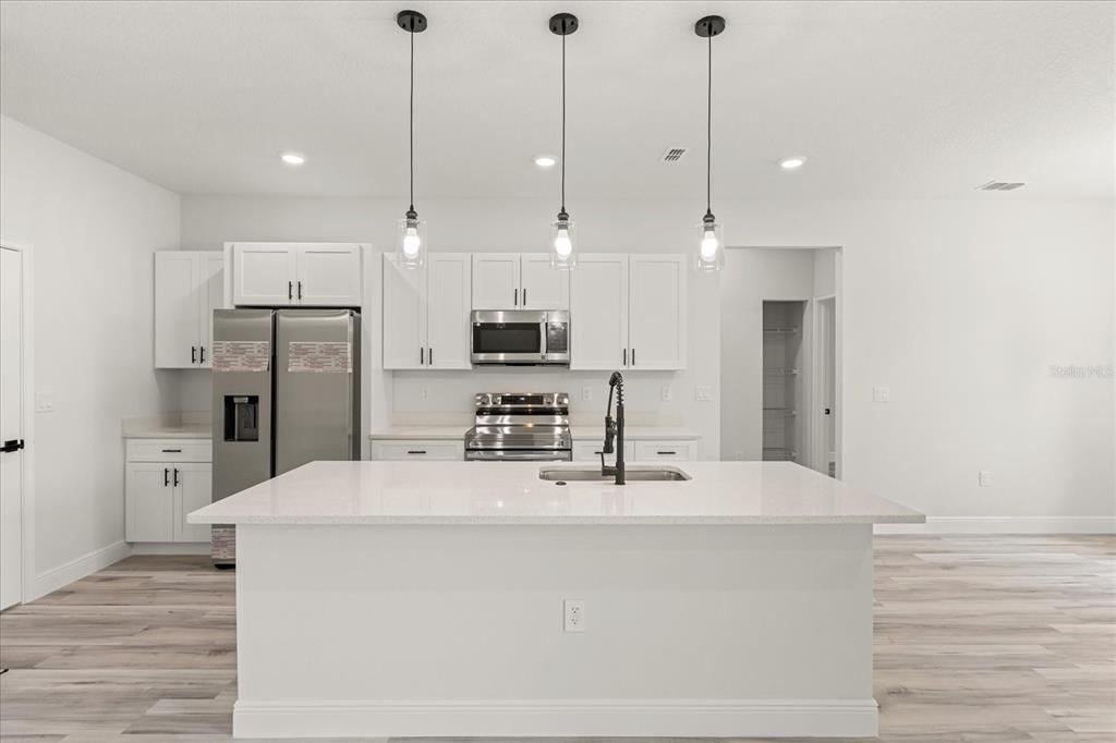 2097 Southwest 153rd Loop Ocala, FL 34481 - Photo 20 of 39 a kitchen with stainless steel appliances kitchen island granite countertop a refrigerator a stove a oven with white cabinets and wooden floor