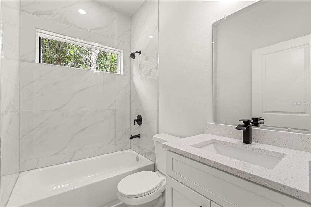 2097 Southwest 153rd Loop Ocala, FL 34481 - Photo 37 of 39 a bathroom with a granite countertop sink a toilet and bathtub