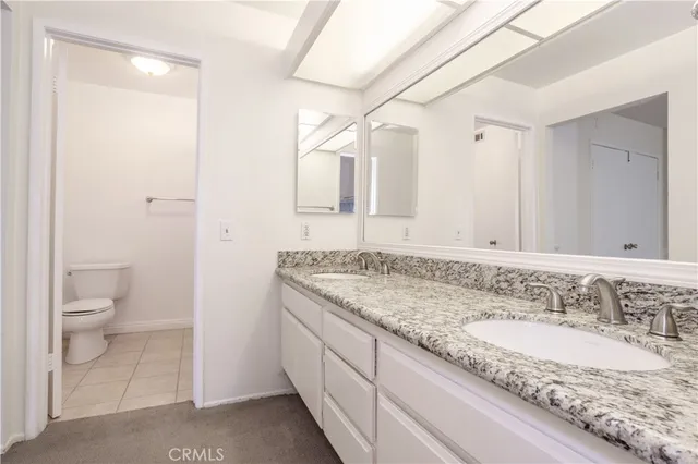 a bathroom with a granite countertop sink a toilet and a large mirror