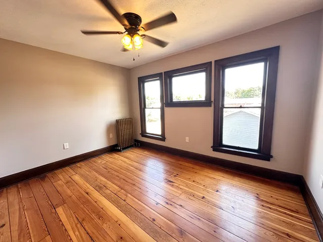 a view of an empty room window and wooden floor
