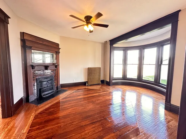 a view of an empty room with window and wooden floor