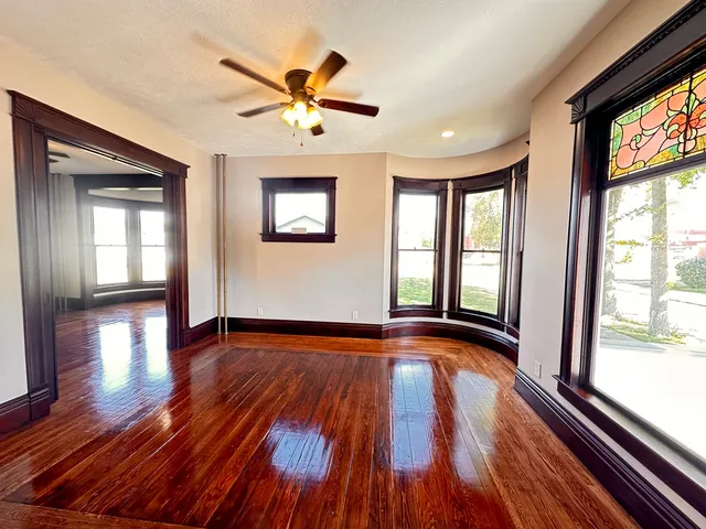 a view of empty room with wooden floor and fan