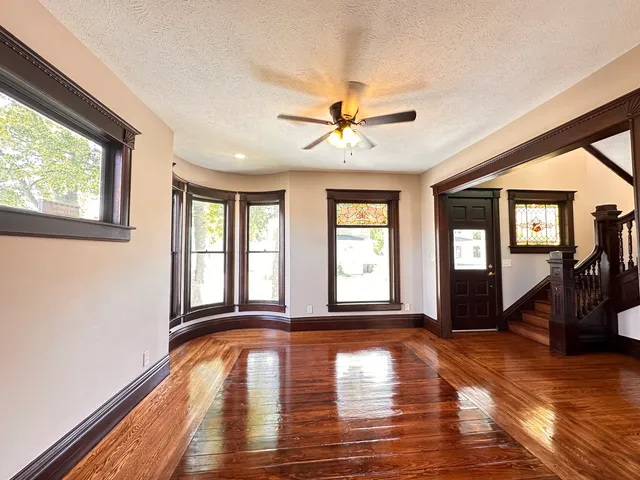 a view of empty room with wooden floor and fan