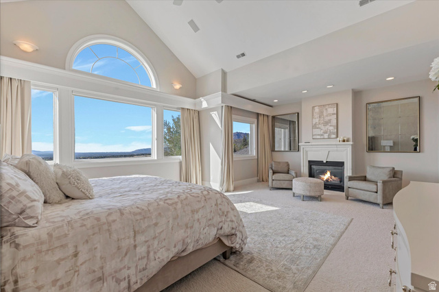 3222 Eagle View Circle Sandy, UT 84092 - Photo 19 of 60 Bedroom with vaulted ceiling, a glass covered fireplace, and light carpet