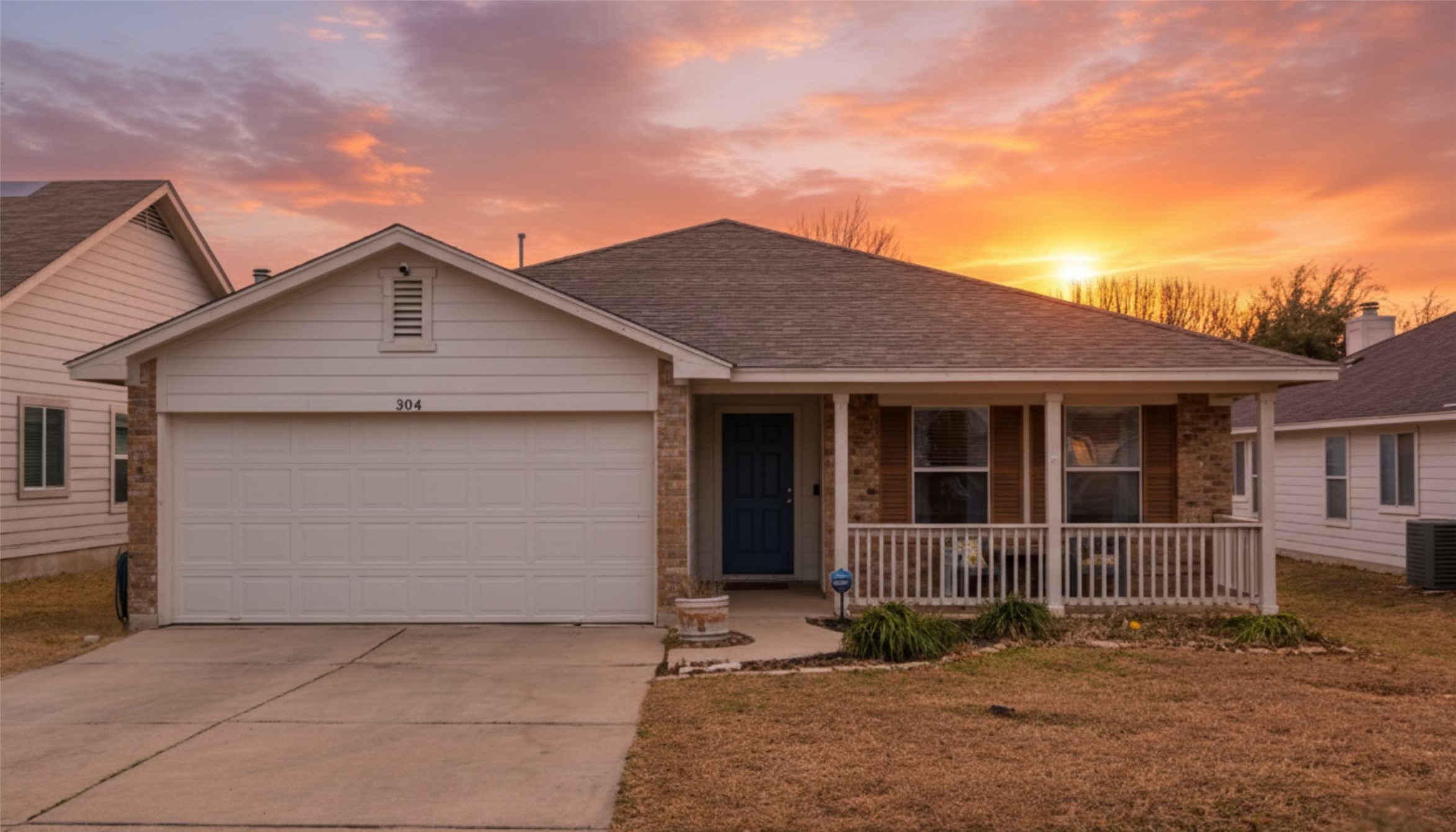 View of front of property with a porch, concrete driveway, brick siding, roof with shingles, and a garage