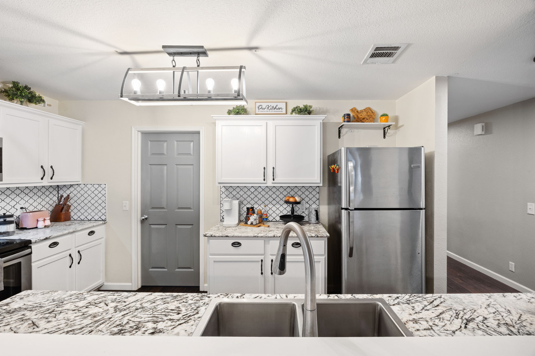 304 Old Peak Road Georgetown, TX 78626 - Photo 13 of 40 Kitchen with stainless steel appliances, white cabinetry, decorative light fixtures, light stone countertops, and a textured ceiling